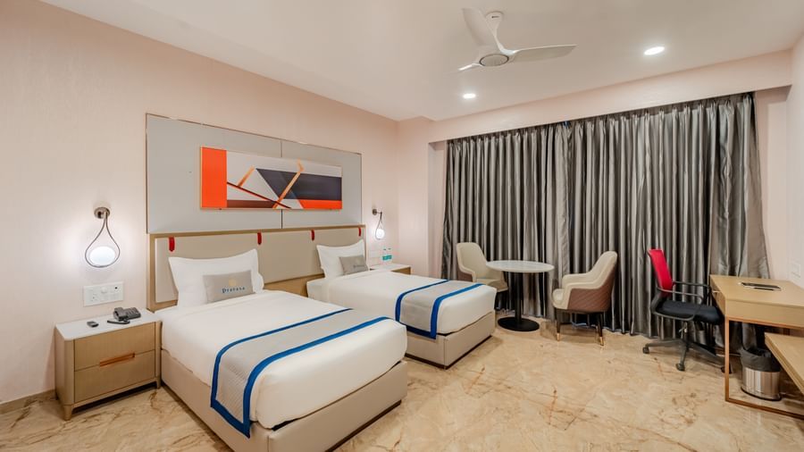 A hotel room with twin beds, a desk, and modern decor | Superior Room | Pravasa Hotel, Vijayapura