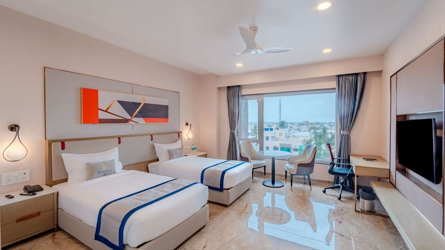 Hotel room with twin beds, a large window, and city view | Superior Room | Pravasa Hotel, Vijayapura
