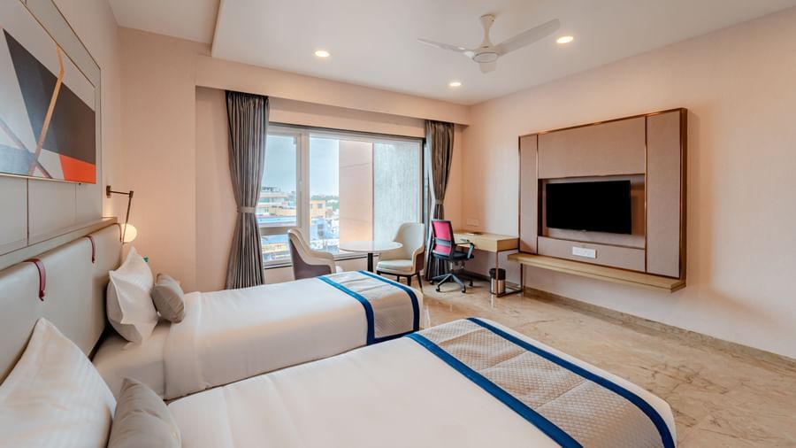 Hotel room with twin beds, a large window, and city view | Superior Room | Pravasa Hotel, Vijayapura
