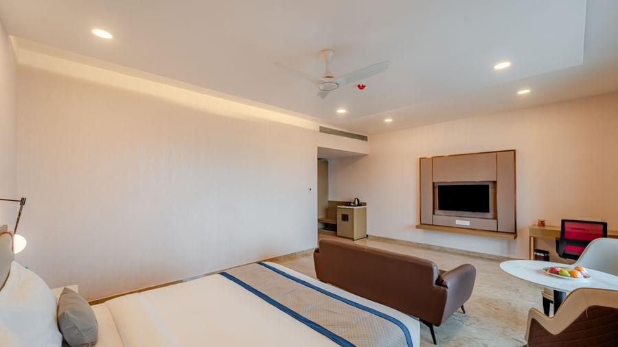  A spacious room with a king-size bed, and a wall-mounted television | Studio Suite | Pravasa Hotel, Vijayapura