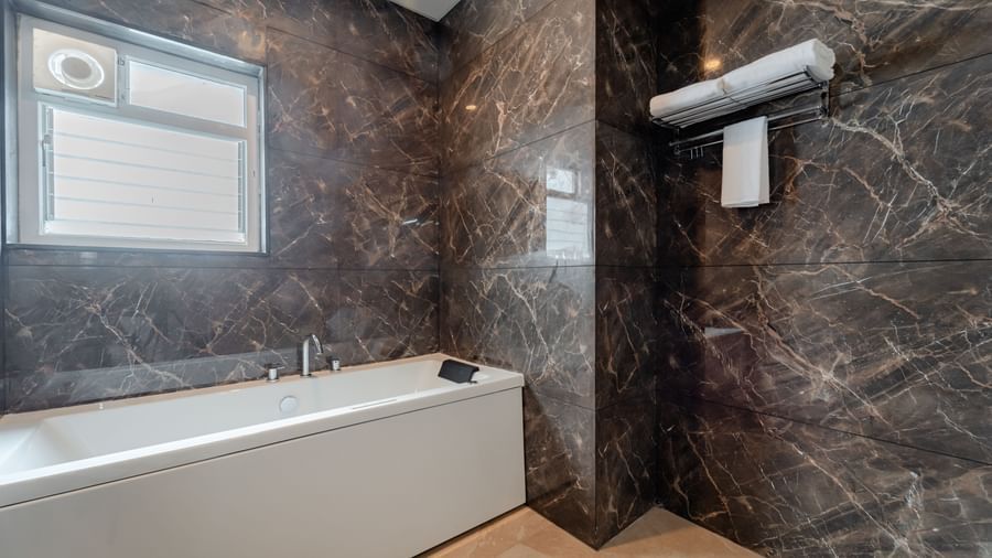 Modern bathroom with a bathtub, shower, and contemporary fixtures | Studio Suite | Pravasa Hotel, Vijayapura