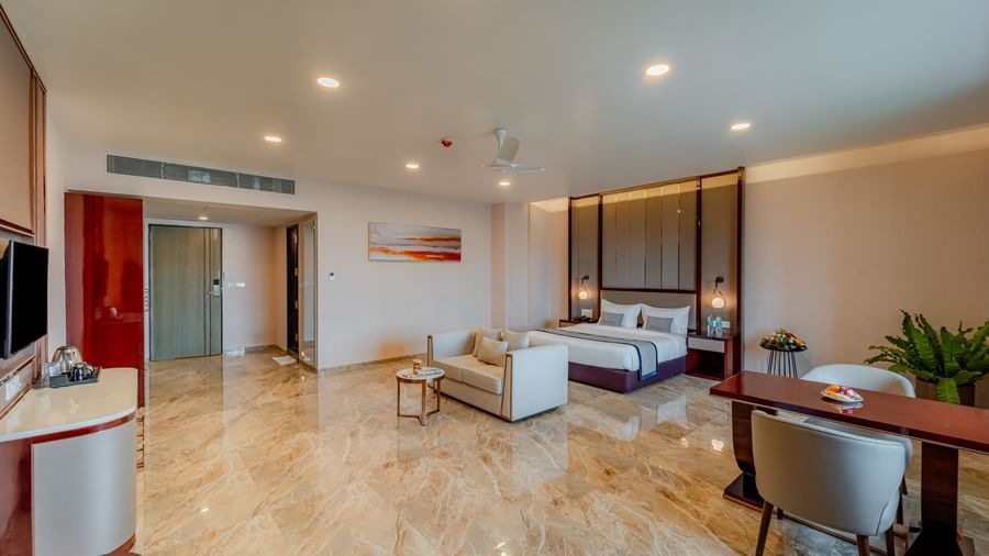 A bright and elegant suite with a bed, living space, and a dining setup | Suite | Pravasa Hotel, Vijayapura