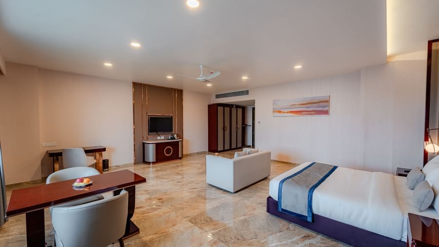  Luxury suite bedroom with a large bed, sofa, and dining area | Suite | Pravasa Hotel, Vijayapura