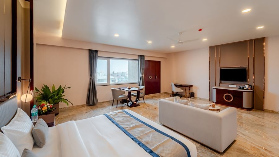 Spacious suite featuring a comfortable bed, lounge area, and city views | Suite | Pravasa Hotel, Vijayapura