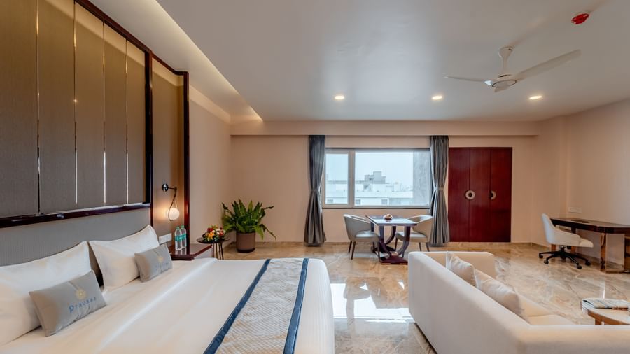 A apacious suite featuring a comfortable bed, lounge area, and city views | Suite | Pravasa Hotel, Vijayapura