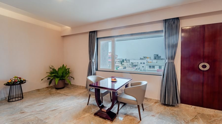 Expansive suite offering a large bed, seating, and a view of the outside | Suite | Pravasa Hotel, Vijayapura