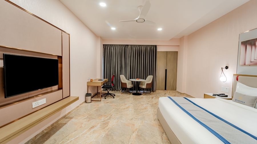 Well-appointed hotel room with a king bed, flat-screen TV, and seating area | Premium Room | Pravasa Hotel, Vijayapura