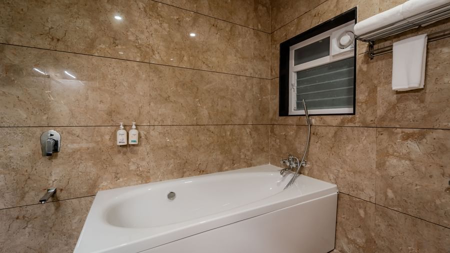 Close-up of a white bathtub in a marble-tiled bathroom | Premium Room | Pravasa Hotel, Vijayapura