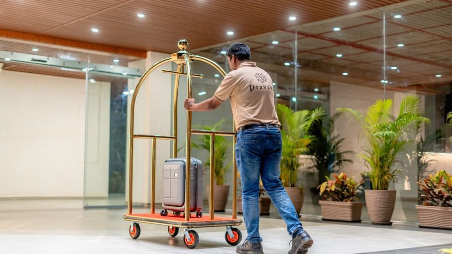 Hotel staff member pushing a luggage cart at Pravasa Hotel | Pravasa Hotel, Vijayapura