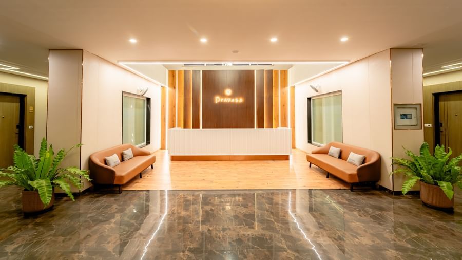 Reception area of the hotel with 2 sofas and potted plants | Pravasa Hotel, Vijayapura