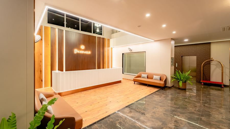 Another shot of the reception area of the hotel with 2 sofas and potted plants | Pravasa Hotel, Vijayapura