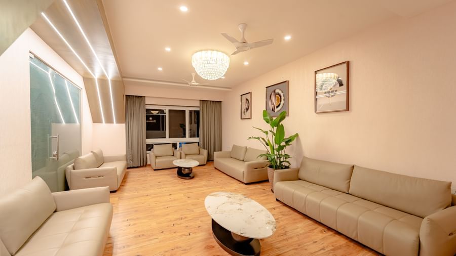 A well-lit waiting lounge with light-colored sofas and ambient lighting | Pravasa Hotel, Vijayapura