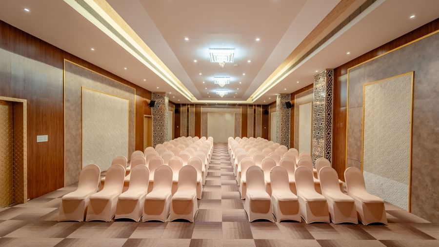 A ballroom set up with rows of beige chairs for a presentation or conference | Meetings & Events | Pravasa Hotel, Vijayapura