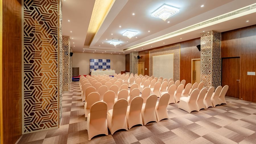 Ballroom set up with rows of beige chairs for a presentation or conference | Meetings & Events | Pravasa Hotel, Vijayapura