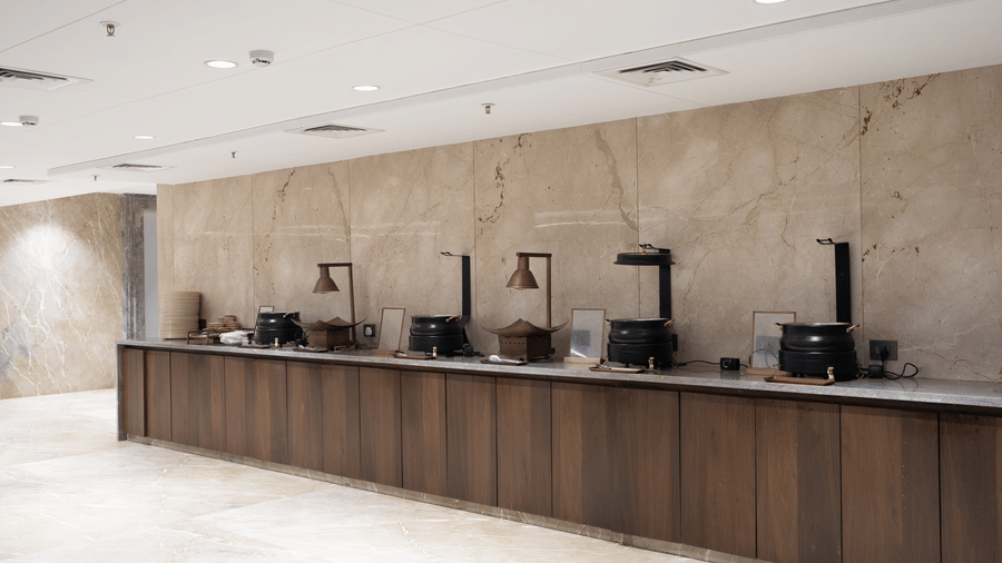 A long, sleek wooden buffet counter set against a marble wall in a banquet facility - Praveg's Grand Eulogia, Ahmedabad