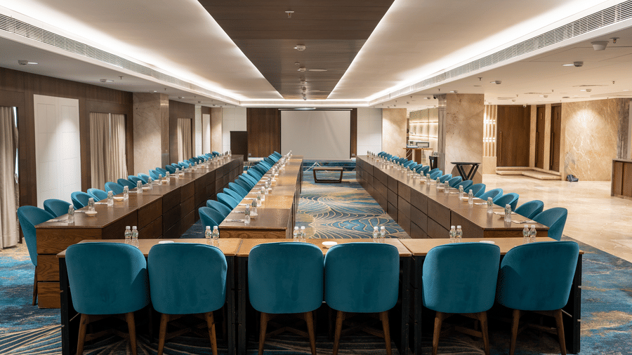 A formal corporate meeting room with teal velvet chairs and modern ceiling lighting - Praveg's Grand Eulogia, Ahmedabad