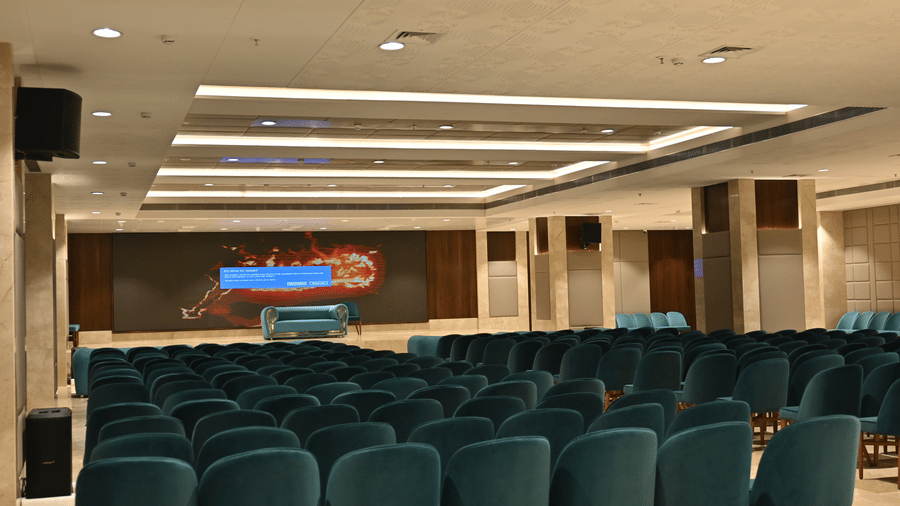 Rows of plush velvet chairs are arranged across a large room facing a main stage in the Eminence banquet hall at Praveg's Grand Eulogia, Ahmedabad.