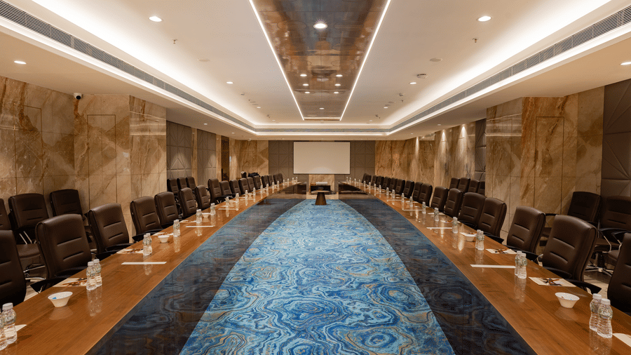 A wide-angle view of a luxury boardroom with a long wooden table and blue patterned carpet - Praveg's Grand Eulogia, Ahmedabad