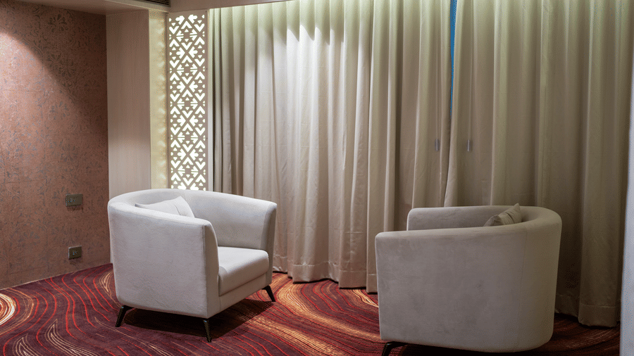 A cosy seating area in a hotel room with two plush armchairs and warm ambient lighting - Praveg's Grand Eulogia, Ahmedabad