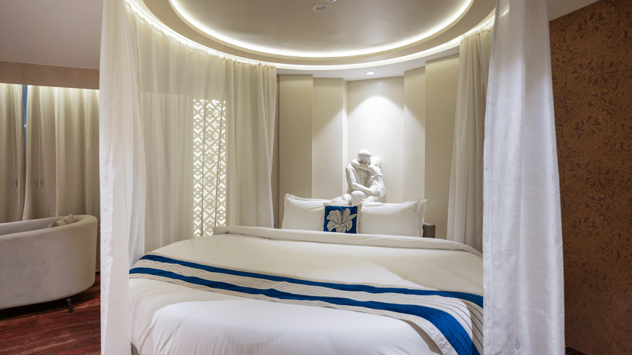 A close-up of a circular bed setup with soft white curtains and a decorative religious idol on the headboard - Praveg's Grand Eulogia, Ahmedabad