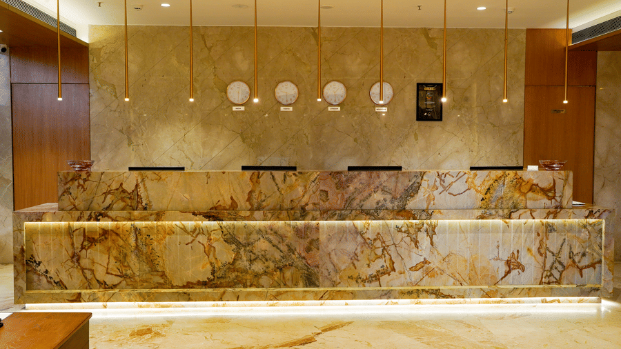A sophisticated marble reception desk with hanging pendant lights and a warm, inviting glow - Praveg's Grand Eulogia, Ahmedabad