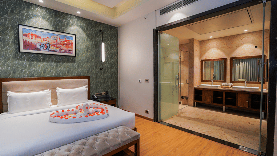 A room with a bed decorated with petals and an attached glass-walled bathroom at Pushkara Resort & Spa.