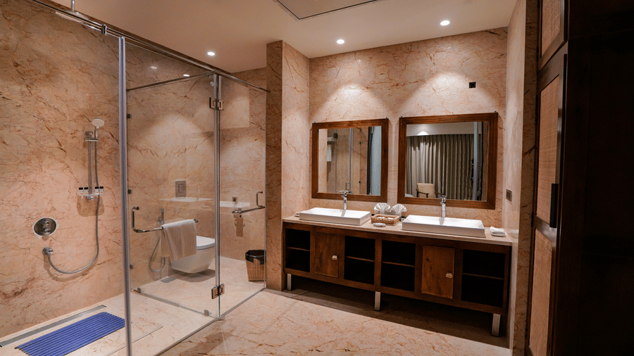 The elegantly designed resort bathroom features two vessel sinks, wood cabinetry, and a large walk-in shower at Pushkara Resort & Spa.