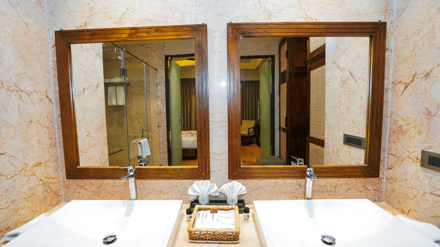 A close-up of the double vanity area with square white sinks and matching mirrors at Pushkara Resort & Spa.