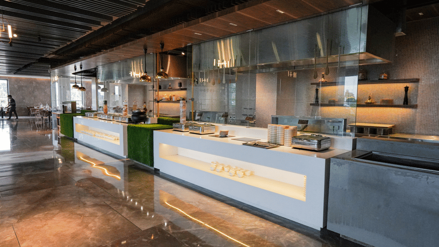 A bright, modern open kitchen and buffet serving area with sleek stainless steel accents at Pushkara Resort & Spa.