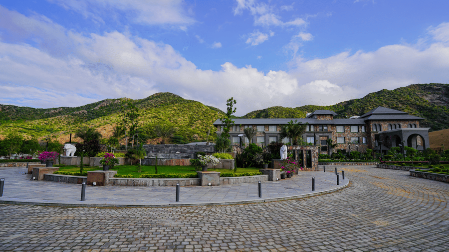 A long view of the main resort building from the driveway, showcasing its modern architecture and the landscaped grounds.