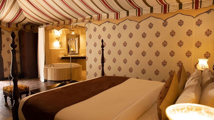 Side view of a room with a bed and lamps beside the bed at Rajasthali Resort & Spa Jaipur.