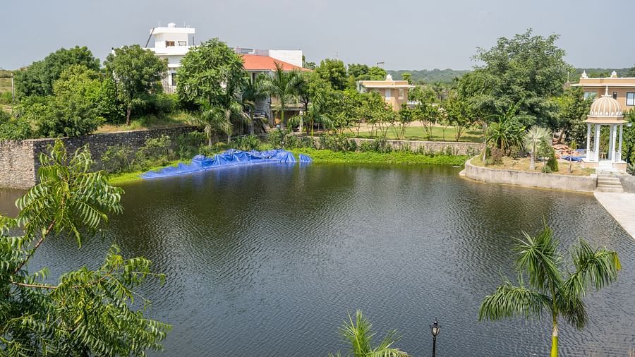 An image of a water body surrounded by lush greenery - Rajbagh Wellness, Udaipur