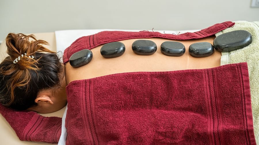 A woman laying on her face receiving a hot stone therapy - Rajbagh Wellness, Udaipur