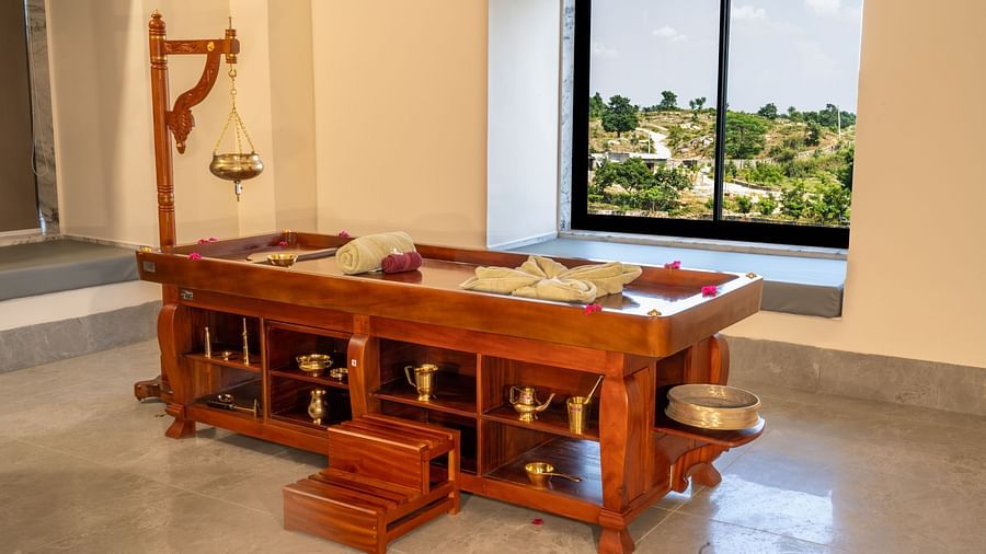 An image of a wooden bed with drawers and cabinets where spa equipment and products are kept - Rajbagh Wellness