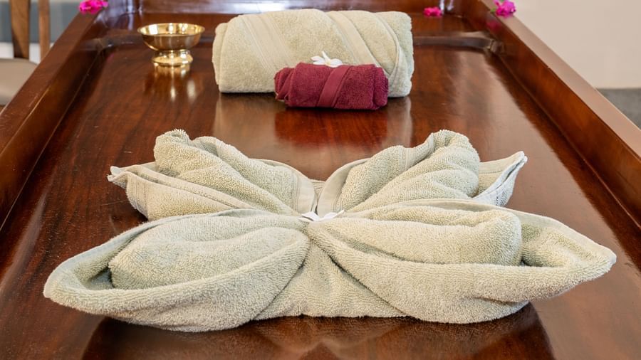 An image of a wooden bed where decorated towels are placed at Rajbagh Wellness