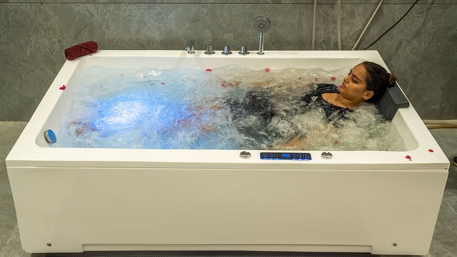 An image of a woman laying on a tub full of ice and water - Rajbagh Wellness