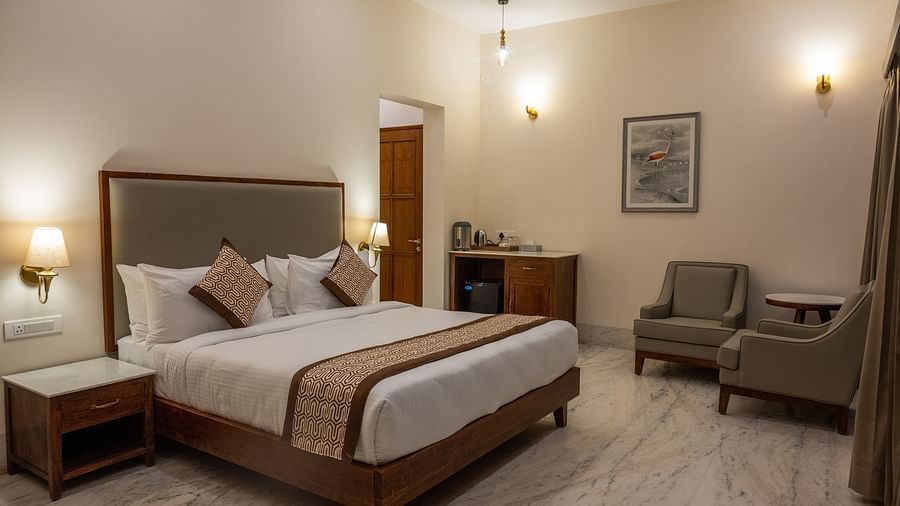 An image of our rooms with a double bed, warm lighting and cosy chairs - Rajbagh Wellness, Udaipur