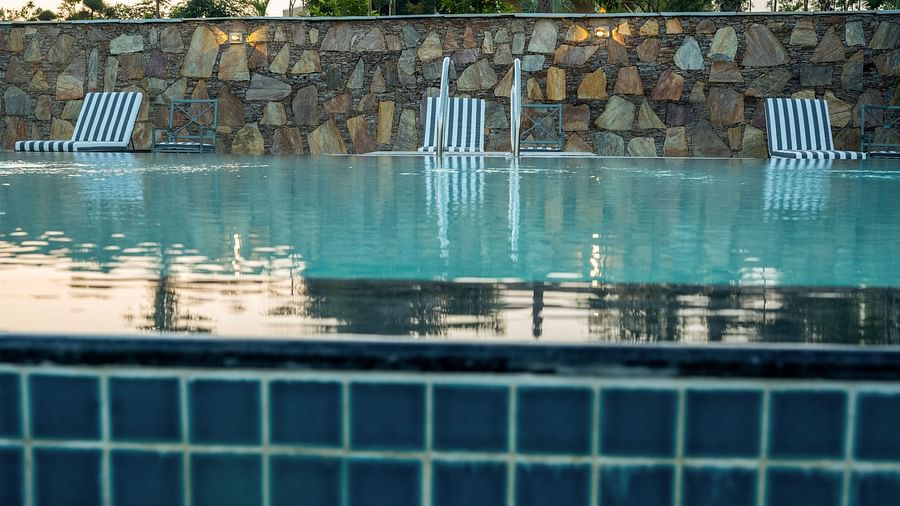 A close-up of the pristine pool with crystal-clear water, set against the rustic charm of a brick wall in the background - Rajbagh Wellness, Udaipur