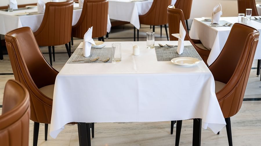 A close up shot a table at our restaurant covered in white cloth and two cosy chairs placed on either side of it - Rajbagh Wellness, Udaipur