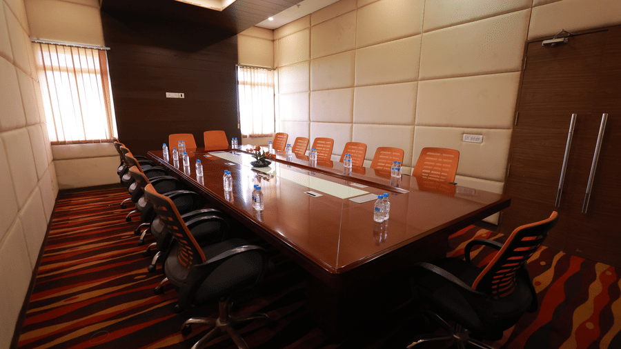 A small, formal boardroom with a long wooden table and ergonomic chairs at Ramada by Wyndham Bodh Gaya Mahabodhi.