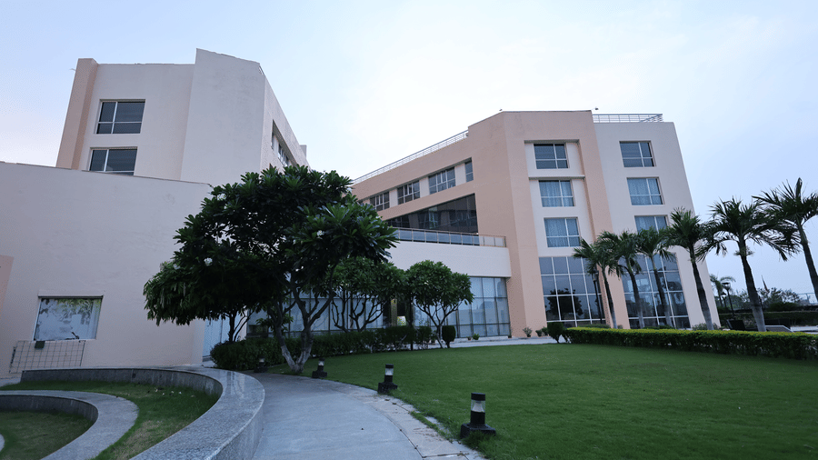 A wide view of Ramada by Wyndham Bodh Gaya Mahabodhi showcasing a large, well-kept lawn and planted trees.