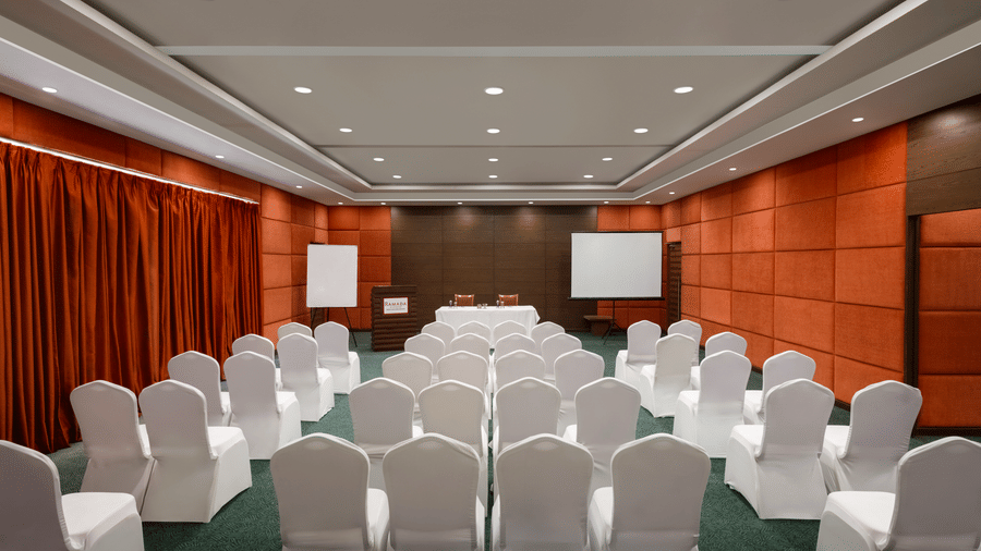 Banquet hall Maitri at Ramada by Wyndham Bodh Gaya Mahabodhi featuring rows of chairs and a projection screen setup for corporate events.