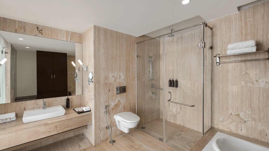 Bathroom of the King Suite at Ramada by Wyndham Bodh Gaya Mahabodhi featuring a western toiler, a walk-in shower area, a bathtub and a large counter top with a sink.