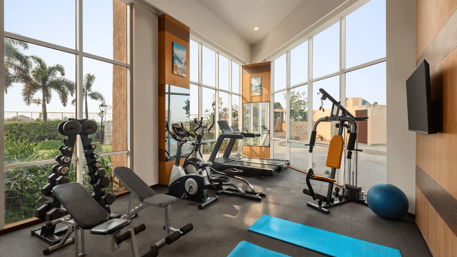 Fitness Centre at Ramada by Wyndham Bodh Gaya Mahabodhi featuring different gym machines and floor-to-ceiling glass windows panels offering the view outside.
