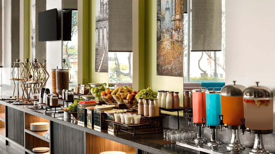 Jalpaan coffee shop at Ramada by Wyndham Bodh Gaya Mahabodhi featuring a buffet spread with different fruits, cereals, and juices.