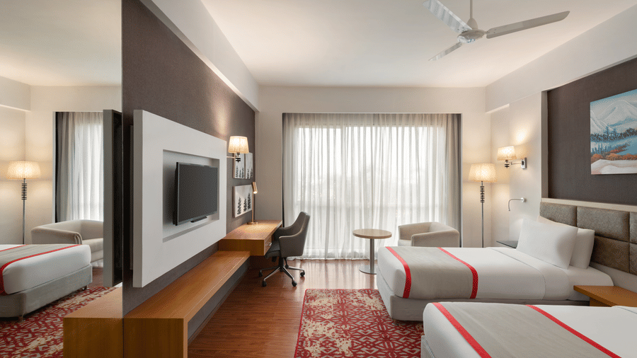 The elegant Standard Twin Room at Ramada by Wyndham Bodh Gaya Mahabodhi offering 2 twin beds, a TV facing the beds, and modern ambient lighting.