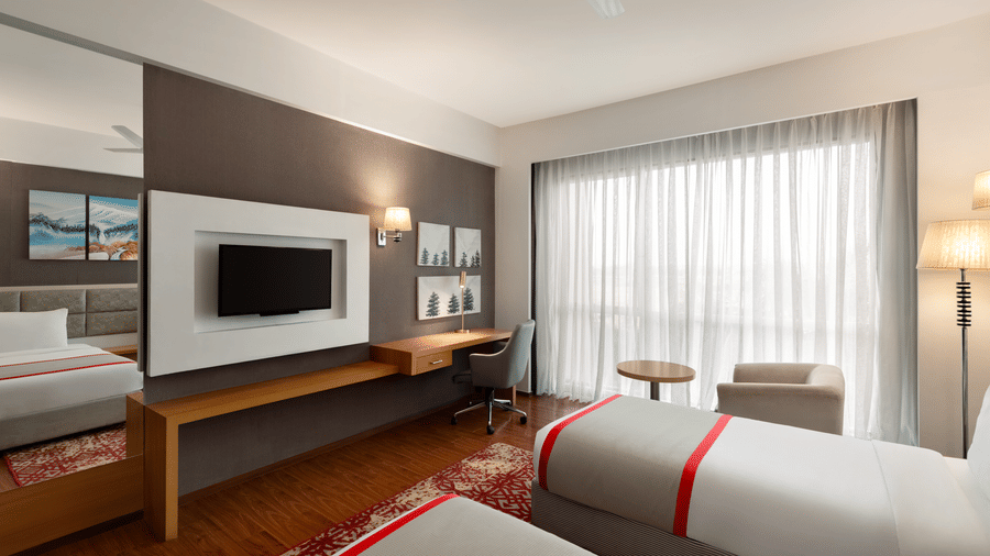 The Standard Twin Room featuring the parallel bed setup facing a television screen at Ramada by Wyndham Bodh Gaya Mahabodhi.