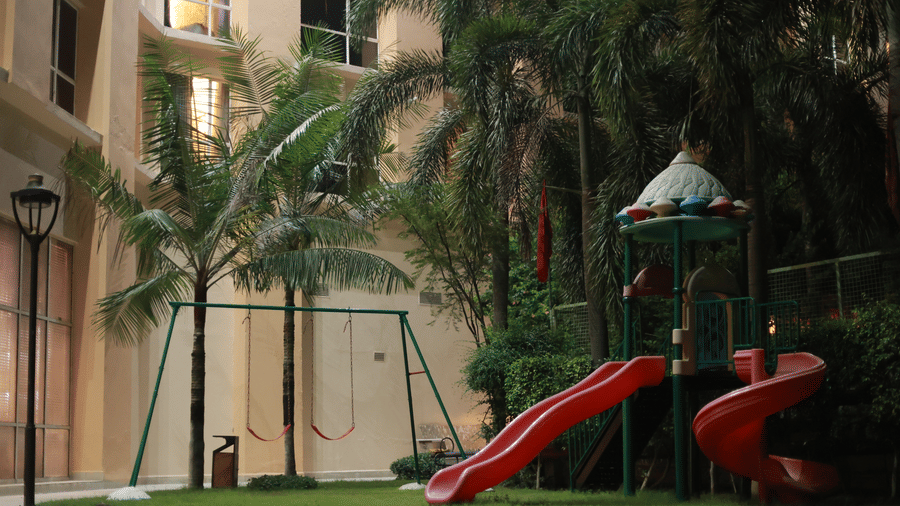 A children's play area on a grassy patch features a red slide and a swing set at Ramada by Wyndham Bodh Gaya Mahabodhi.