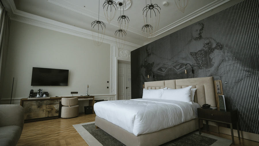 Spacious suite with platform bed, statement mural wall, chandelier, and seating area.
