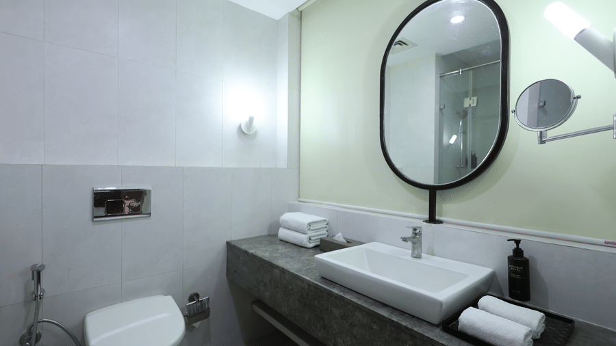 A contemporary bathroom vanity area shows a large sink, mirror, and toiletries - Ramada by Wyndham Bodh Gaya Mahabodhi